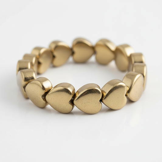 A premium catalog product shot of the finished gold tone heart hematite accent bracelet resting symmetrically on a pure white luxury studio background.
